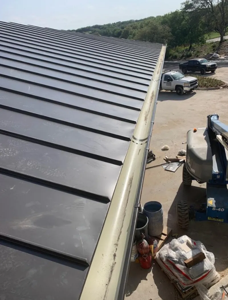 Standing seam panel and gutter detail on a metal roofing jobsite in Alden